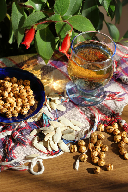 a bowl of nuts next to a glass of tea
